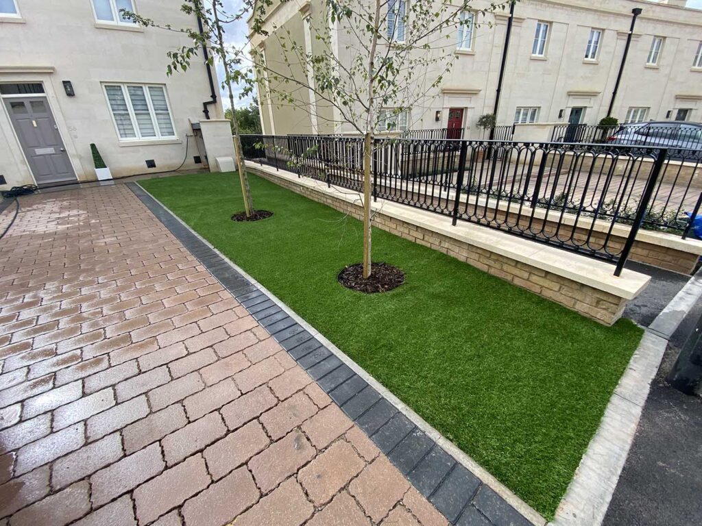 A small section of artificial grass with a brick garden path, an example of landscaping in a front garden