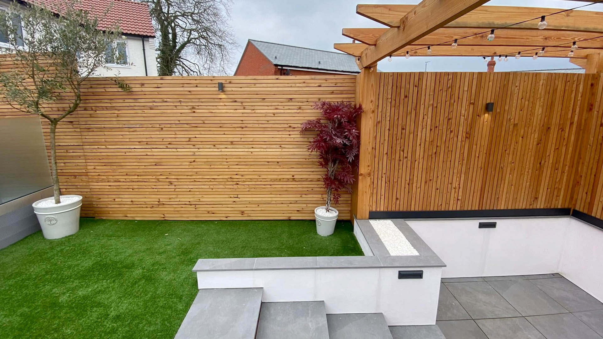 A wooden slatted fence with garden patio area and steps