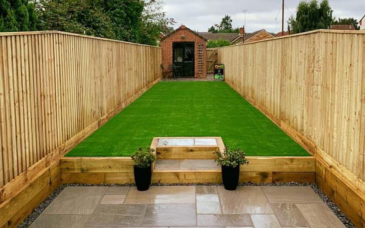 An example of a small garden with artificial grass, patio area, modern fencing and a shed
