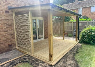 Wooden pergola attached to a house with decking inside